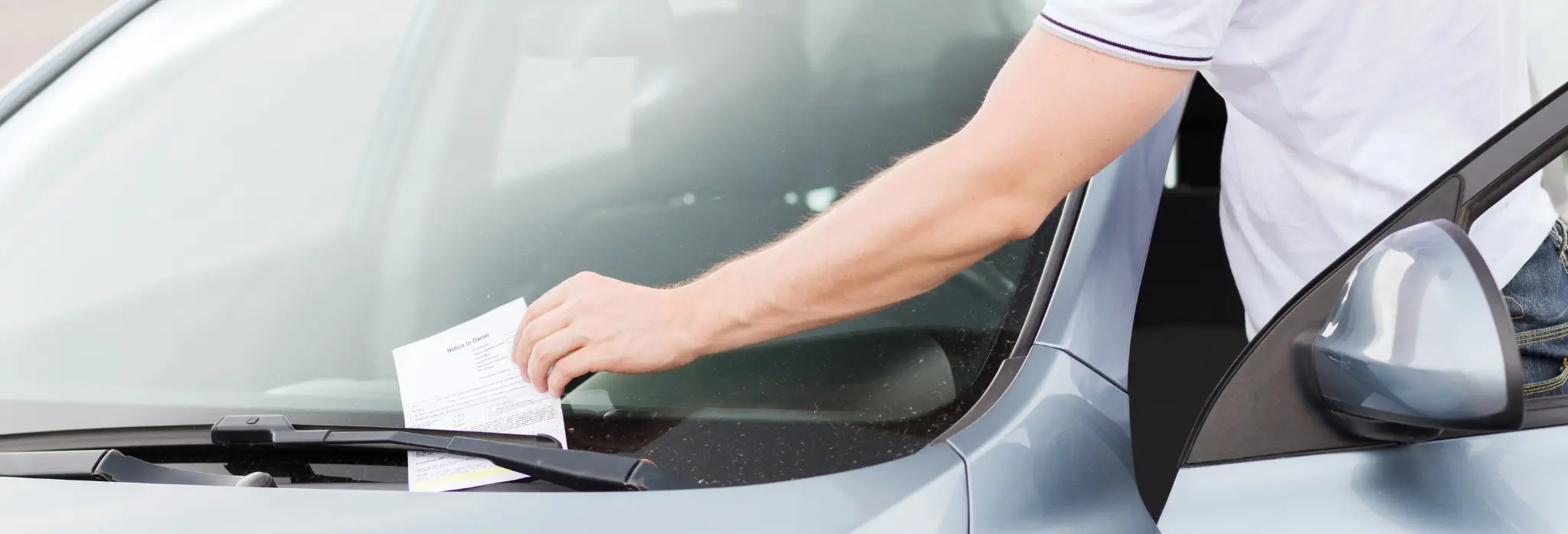 Άντρας βρίσκει κλήση στο παρτμπρίζ του αυτοκινήτου.